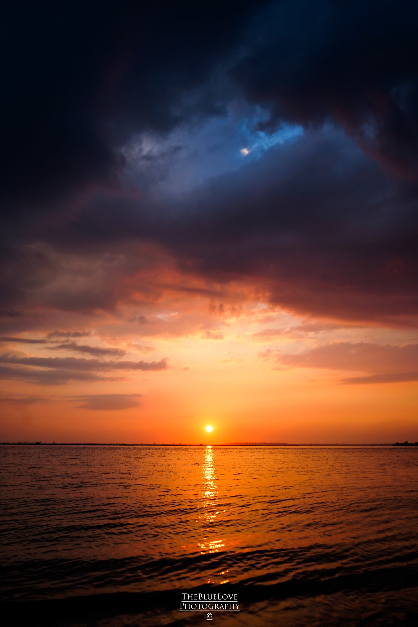 Stormy Dusk: Dark Blue Clouds and Fiery Orange Sunset